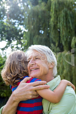Happy grandfather hugging grandson at yard