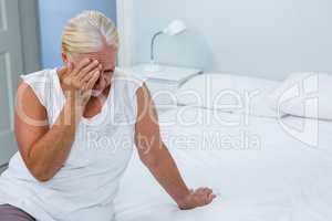 Upset senior woman touching head at home
