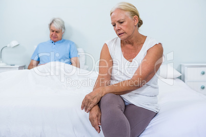 Sad senior couple sitting in bedroom