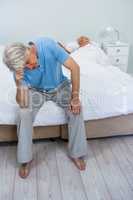 Tensed senior man touching head while woman sleeping on bed