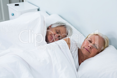 Side view of senior couple sleeping on bed