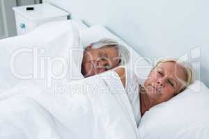 Side view of senior couple sleeping on bed