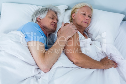 High angle view of senior couple sleeping on bed