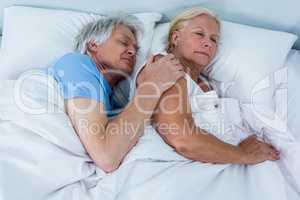 High angle view of senior couple sleeping on bed
