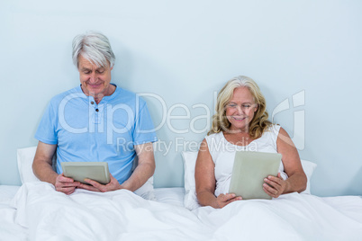 Happy retired couple using digital tablets