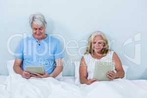 Happy retired couple using digital tablets