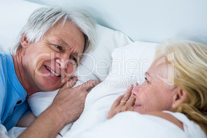 Close-up of smiling senior couple sleeping on bed
