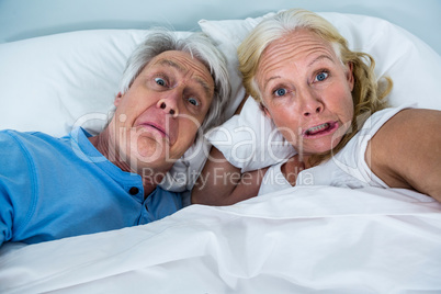 Retired couple making faces while relaxing on bed