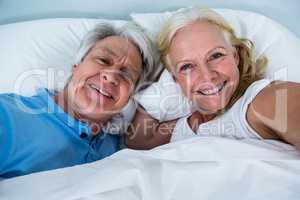 Portrait of cheerful retired couple sleeping on bed