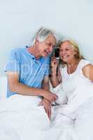 Happy retired couple listening to music through smartphone
