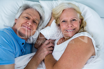 Portrait of cheerful retired couple relaxing on bed