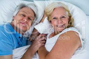Portrait of cheerful retired couple relaxing on bed