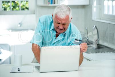 Senior man using laptop on kitchen counter