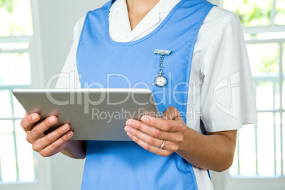 Midsection of nurse holding digital tablet