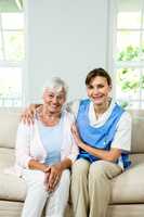 Portrait of happy nurse with senior woman at home