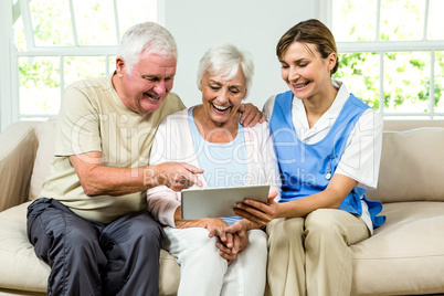 Happy nurse and senior adults holding digital tablet