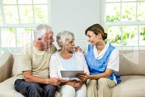 Senior man and woman with nurse at home