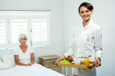 Portrait of smiling caregiver holding breakfast tray