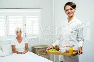 Portrait of smiling caregiver holding breakfast tray