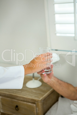 Cropped image of doctor giving water to senior patient