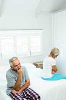 Sad aged man and woman sitting on bed