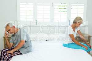 Sad senior man and woman sitting on bed