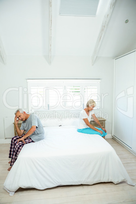 Senior man and woman sitting on bed