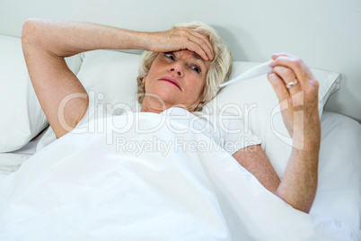 High angle view of senior woman checking thermometer