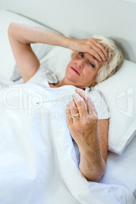 High angle view of aged woman checking thermometer