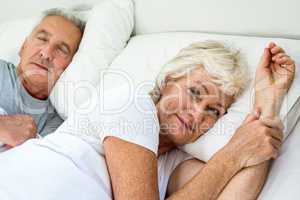 Portrait of smiling senior woman with man relaxing on bed