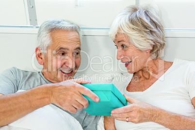 Senior man gifting to woman on bed