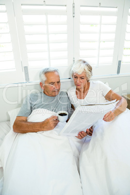 High angle view of senior man and woman reading newspaper