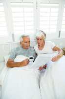 High angle view of senior man and woman reading newspaper