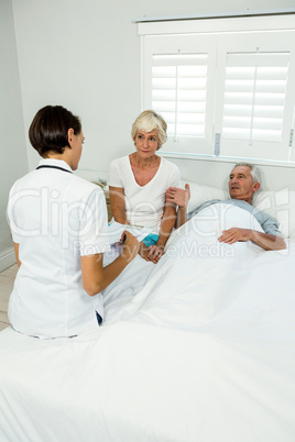 Female caregiver with senior couple at home
