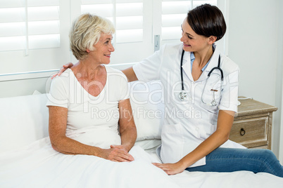 Smiling female doctor assisting senior woman