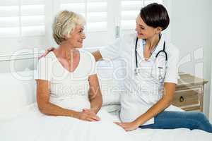 Smiling female doctor assisting senior woman