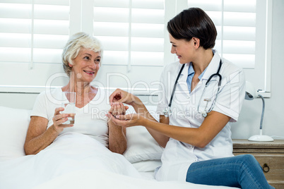 Smiling female doctor giving medicine to senior woman