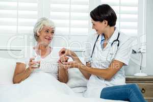 Smiling female doctor giving medicine to senior woman