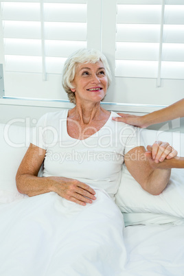 Cropped image of doctor holding senior woman hand
