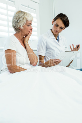 Female doctor with senior woman holding clipboard