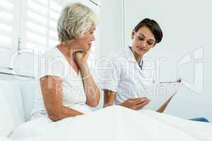 Female doctor sitting with senior woman