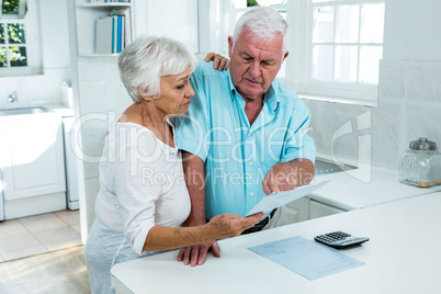 Senior couple holding document at home