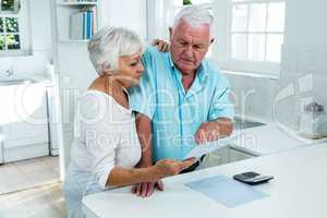 Senior couple holding document at home