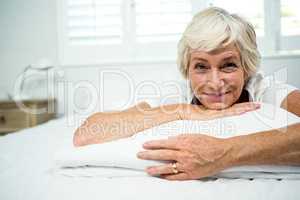 Portrait of smiling woman relaxing on bed