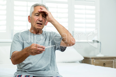 Aged man checking thermometer at home