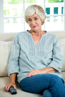 Thoughtful senior woman sitting on sofa