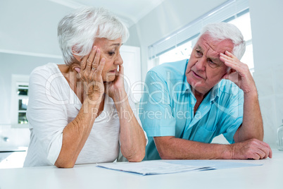 Tensed senior couple talking to each other at home