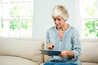 Senior woman using digital tablet on sofa