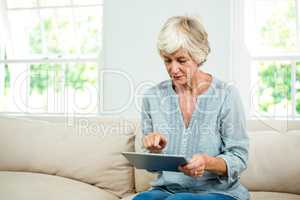 Senior woman using digital tablet on sofa