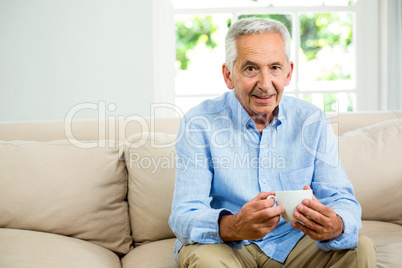 Portrait of smiling senior man holding coffee cup